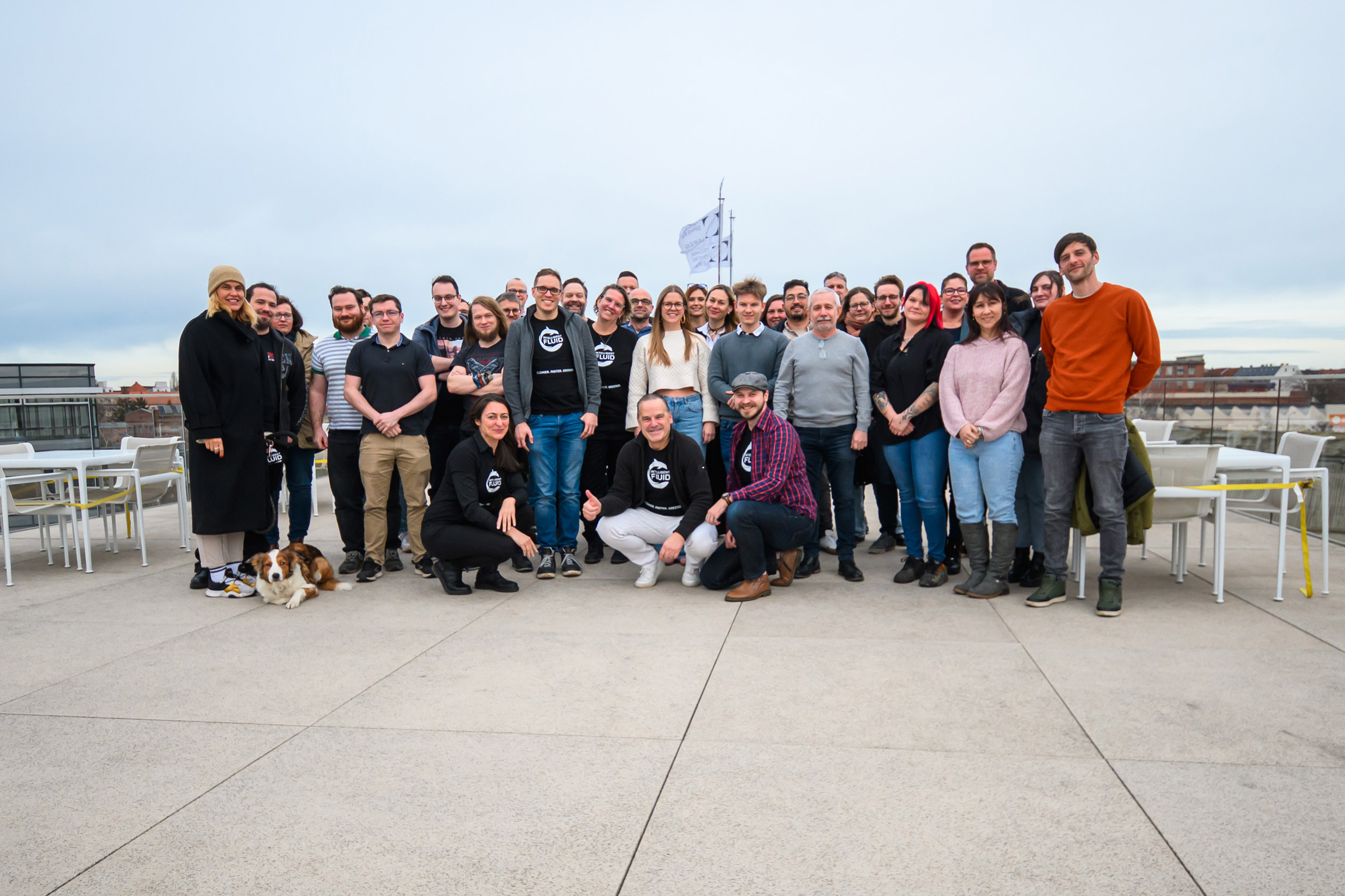 ein Gruppenfoto der Mitarbeiter der Firma intelligent fluids. Alle stehen auf einem Dach. Im Hintergrund kann man den 